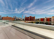 Thumbnail 24 of 32 - A balcony with a glass railing overlooking a cityscape.