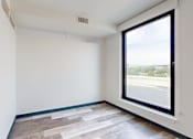 Thumbnail 16 of 32 - A room with a large window and a wooden floor.