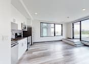Thumbnail 10 of 32 - A modern kitchen with white cabinets and a large window overlooking the landscape.