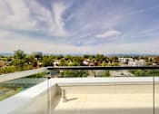 Thumbnail 23 of 32 - A balcony with a glass railing overlooks a cityscape.