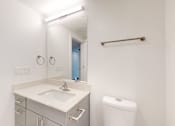 Thumbnail 19 of 32 - A white bathroom with a sink, toilet, and mirror.