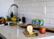 Thumbnail 10 of 33 - a kitchen counter with an apple on a cutting board