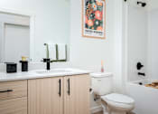 Thumbnail 13 of 30 - The Wes Gresham Oregon Apartments A bathroom with a white toilet, a sink, and a bathtub.