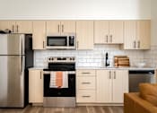 Thumbnail 14 of 30 - The Wes Gresham Oregon Apartments  A modern kitchen with wooden cabinets and a stainless steel refrigerator.