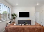 Thumbnail 18 of 30 - a living room with a brown couch and a tv on the wall