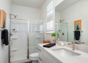 Thumbnail 23 of 30 - a bathroom with a sink and a shower and a mirror
