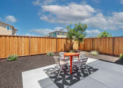 Thumbnail 25 of 30 - a patio with a table and chairs in front of a wooden fence