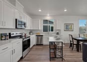 Thumbnail 1 of 30 - a kitchen and dining area with white cabinets and stainless steel appliances