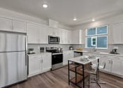 Thumbnail 2 of 30 - a kitchen with white cabinets and a table with chairs