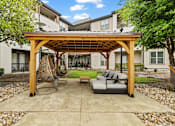 Thumbnail 29 of 33 - A patio with a wooden pergola and a grey couch.