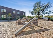 Thumbnail 19 of 28 - A playground with a seesaw in front of a building.