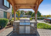 Thumbnail 12 of 28 - A modern outdoor kitchen with a grill and sink.