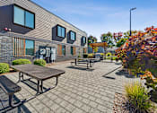 Thumbnail 11 of 28 - A modern building with a patio and picnic table.