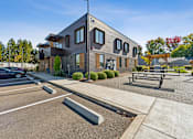 Thumbnail 26 of 28 - A modern building with a parking lot in front.