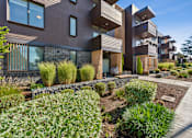 Thumbnail 23 of 28 - A modern house with a brown exterior and a landscaped front yard.