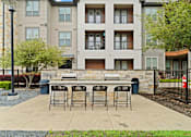 Thumbnail 25 of 33 - A patio with a table and chairs is in front of a building.