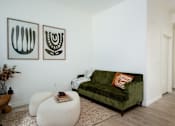 Thumbnail 20 of 30 - The Wes Gresham Oregon Apartments A living room with a green couch and two white ottomans.