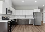 Thumbnail 6 of 21 - A modern kitchen with stainless steel appliances and wooden floors.