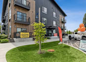 Thumbnail 4 of 21 - A leasing office sign is displayed in front of a modern building.