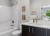 Thumbnail 11 of 21 - A white bathroom with a toilet, sink, and shower.