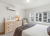 Thumbnail 15 of 38 - A bedroom with a large bed, a dresser, and a window overlooking a building.