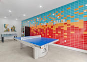 Thumbnail 22 of 33 - A ping pong table is in a room with a colorful wall.