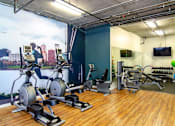 Thumbnail 24 of 29 - A gym with exercise equipment and a cityscape mural on the wall.