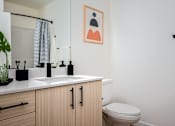 Thumbnail 23 of 30 - The Wes Gresham Oregon Apartments  A bathroom with a toilet, sink, and a painting on the wall.