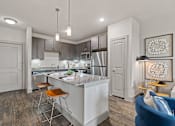 Thumbnail 2 of 33 - A modern kitchen with a bar stool and a blue sofa.