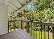 Thumbnail 24 of 25 - A wooden deck with a white house and trees in the background.