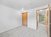 Thumbnail 11 of 25 - A room with a carpeted floor and a wooden door.