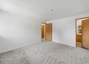 Thumbnail 19 of 25 - A room with a carpeted floor and two wooden doors.