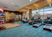 Thumbnail 20 of 32 - a gym with cardio equipment and a large window