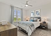 Thumbnail 5 of 33 - A bedroom with a bed, nightstand, and a ceiling fan.