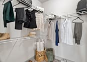 Thumbnail 8 of 33 - A white closet with clothes and shoes hanging on shelves.