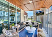 Thumbnail 26 of 53 - A modern balcony with a sofa, chairs, and a TV.