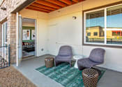 Thumbnail 23 of 35 - A patio with two chairs and ottoman with a green rug.