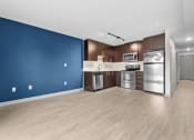 Thumbnail 19 of 28 - an empty room with a blue wall and a kitchen with stainless steel appliances