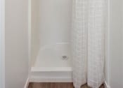 Thumbnail 28 of 33 - a bathroom with a white shower curtain and a blue towel