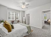 Thumbnail 25 of 28 - A bedroom with a bed, a mirror, and a ceiling fan.