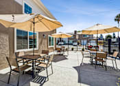 Thumbnail 15 of 28 - A patio with tables and chairs under umbrellas.