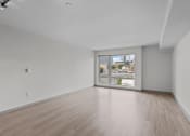 Thumbnail 18 of 28 - an empty living room with wood floors and a large window