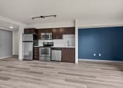 Thumbnail 15 of 28 - an empty room with a blue wall and a kitchen with stainless steel appliances