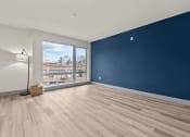 Thumbnail 21 of 28 - a living room with a large window and a blue wall and wooden floors