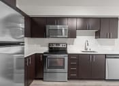Thumbnail 6 of 28 - a kitchen with stainless steel appliances and dark wood cabinets