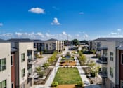 Thumbnail 4 of 53 - A view of a courtyard surrounded by buildings with a blue sky and clouds in the background.