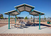 Thumbnail 10 of 35 - A playground with a shelter and benches is set in a sandy area.