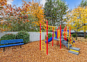 Thumbnail 15 of 18 - A playground with a red and yellow swing set and a blue bench.