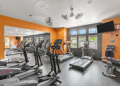 Thumbnail 25 of 43 - a gym with cardio equipment and a flat screen tv