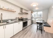 Thumbnail 1 of 33 - a kitchen with white cabinets and a black table and chairs